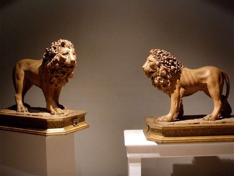 A pair of 19th century terracotta figures of lions with giltwood basement.