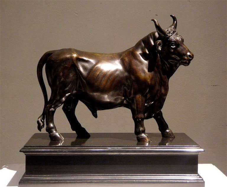 A bronze sculpture, dark patina, depicts bull.