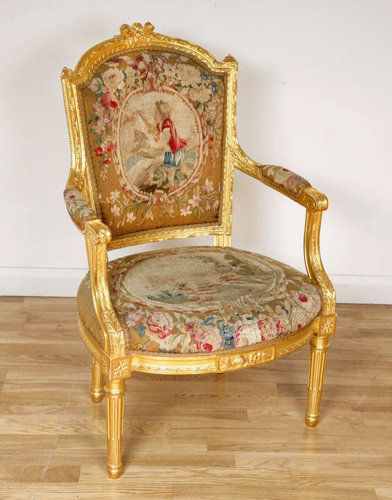 Comprising one canape and eight armchairs, each with arched padded back and bowed seat centred by an oval depicting figures and animals in the manner of Aesop’s Fables, the canape back with the oval flanked by ribbon-tied trophies, with ribbon-tied
