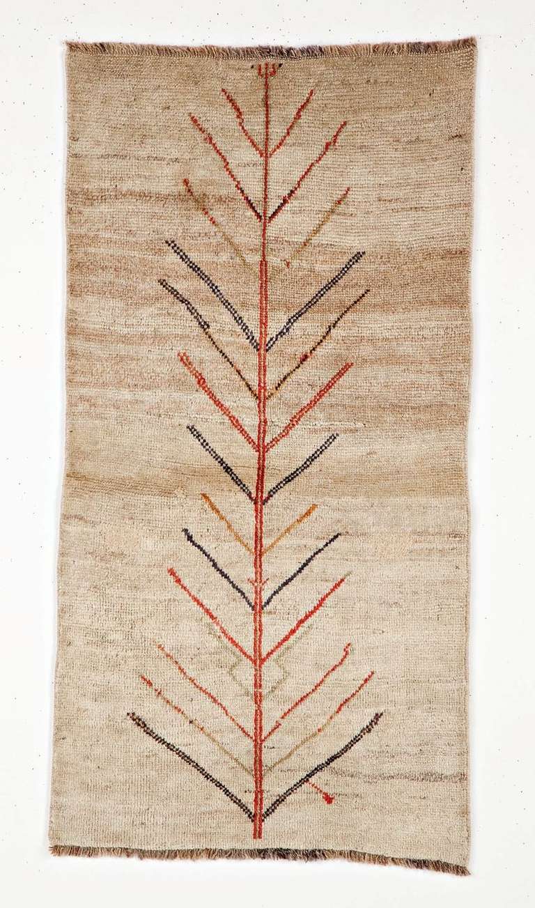 This unique and eye-catching Gabbeh rug is made with extra high pile and extra fine wool yarns very bright and vivid. On a warm beige open field this rug shoes the emblematic character found in early Gabbeh rugs: the Tree of Life, one of the most