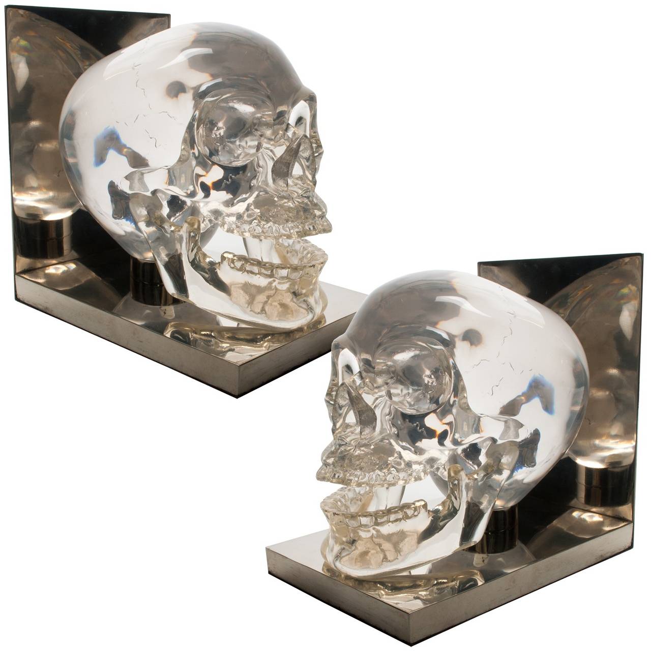 Skull bookends acrylic Lucite steel polished, France, 1970s. Solid cast resin mounted on nickel-plated metal platforms. The skulls are finely detailed and have hinged jaws. Made in France and sold at Harrods in London during the 1970s.
