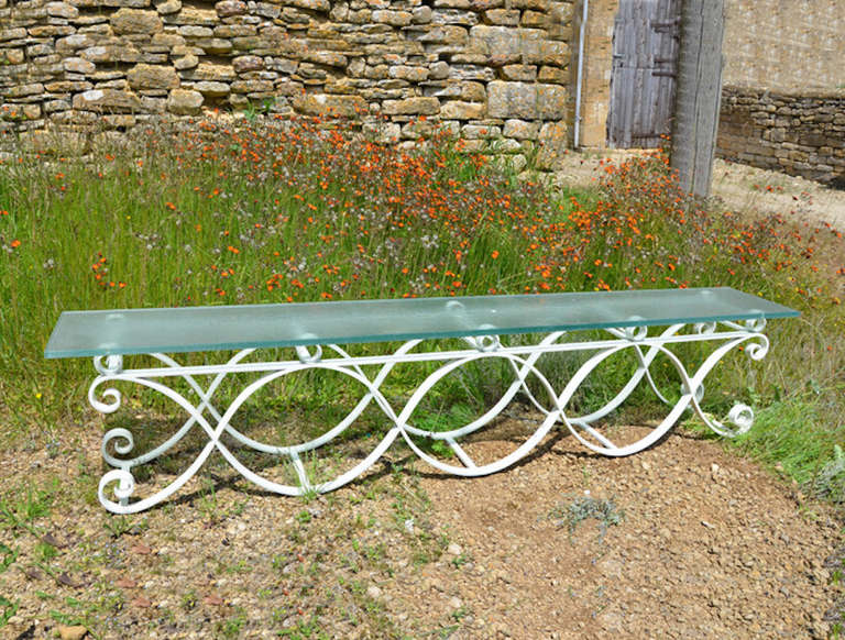 A 20th century iron bench with frosted glass seat.