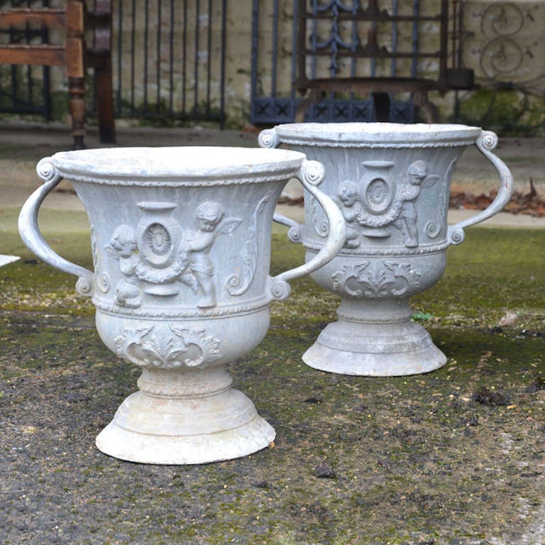 A pair of early 20th century lead urns of campana form having cherub decoration surmounted by simple handles and raised upon a circular socle.
Two pairs available.