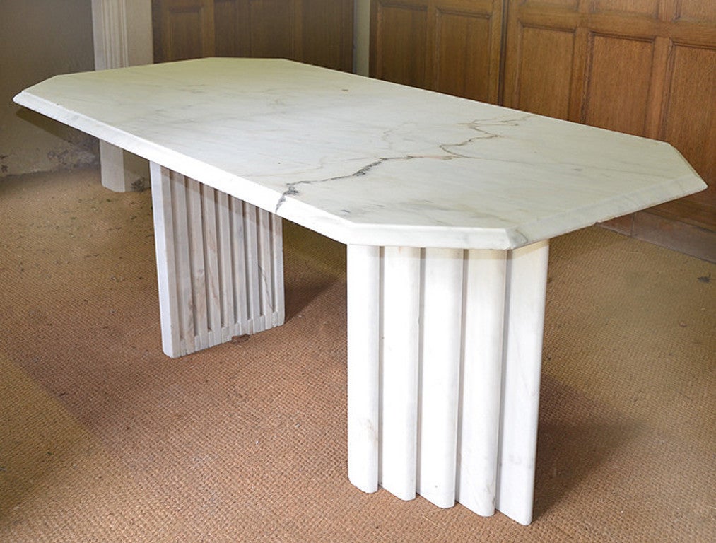 A marble table in the Art Deco style, circa 1930, having a rectangular top supported by two triangular legs made up of laminate marble slabs.