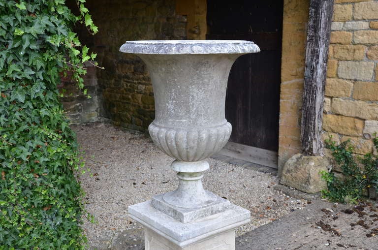 An Italian white marble campana urn, circa 1900, having plain body with lobed base, simple rim moulding, raised upon a waisted socle. This classic design of urn was in production around the turn of the century and was imported to England by J. P.