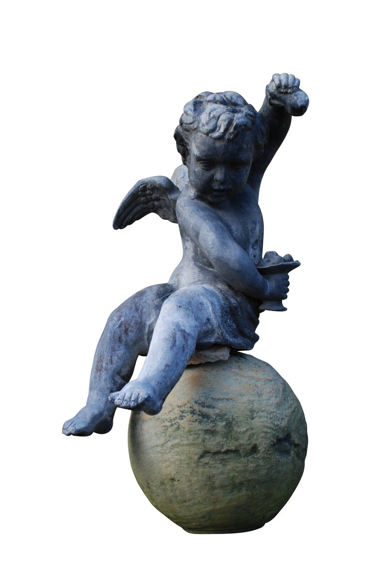 A pair of mid 20th century, circa 1950, winged lead cherubs produced by Crowthers, London.  The model in the Baroque manner, based on the extant figures at Hampton Court, are of two seated frolicking putti, one holding fruit and a bowl, the other