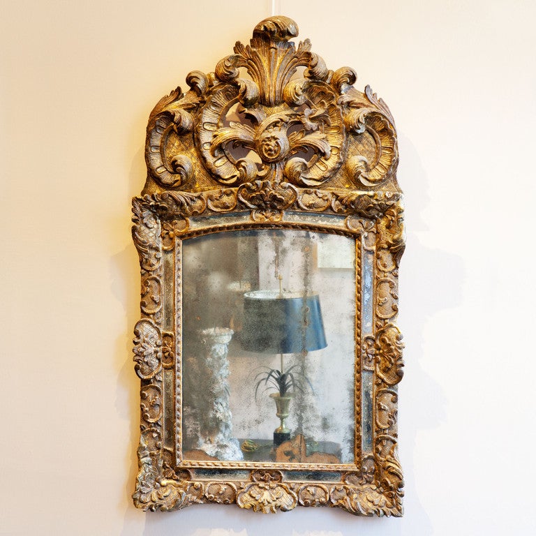 A early 18th century transitional regence / rococo mirror with a original plate, inset borders and silvered frame with cross hatching and foliate scrolls.