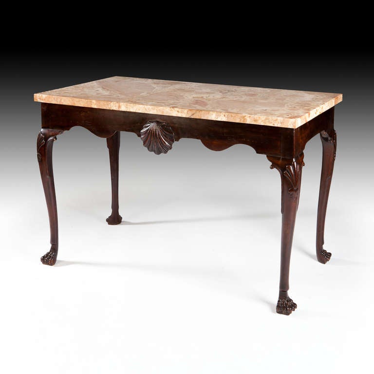 A fine mid 18th century Irish mahogany side table with shaped apron and applied shell, supported on cabriol legs terminating with hairy paw feet. With a brecia marble top.
