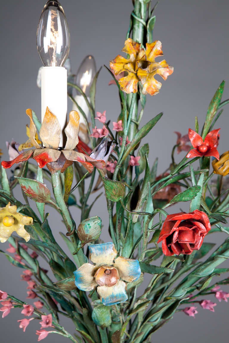 A very unusual mid 20th century painted tole chandelier in the form of a bunch of flowers, tied at the base and flared out around a central ivy clad stem with roses, peonies, and tulips. 