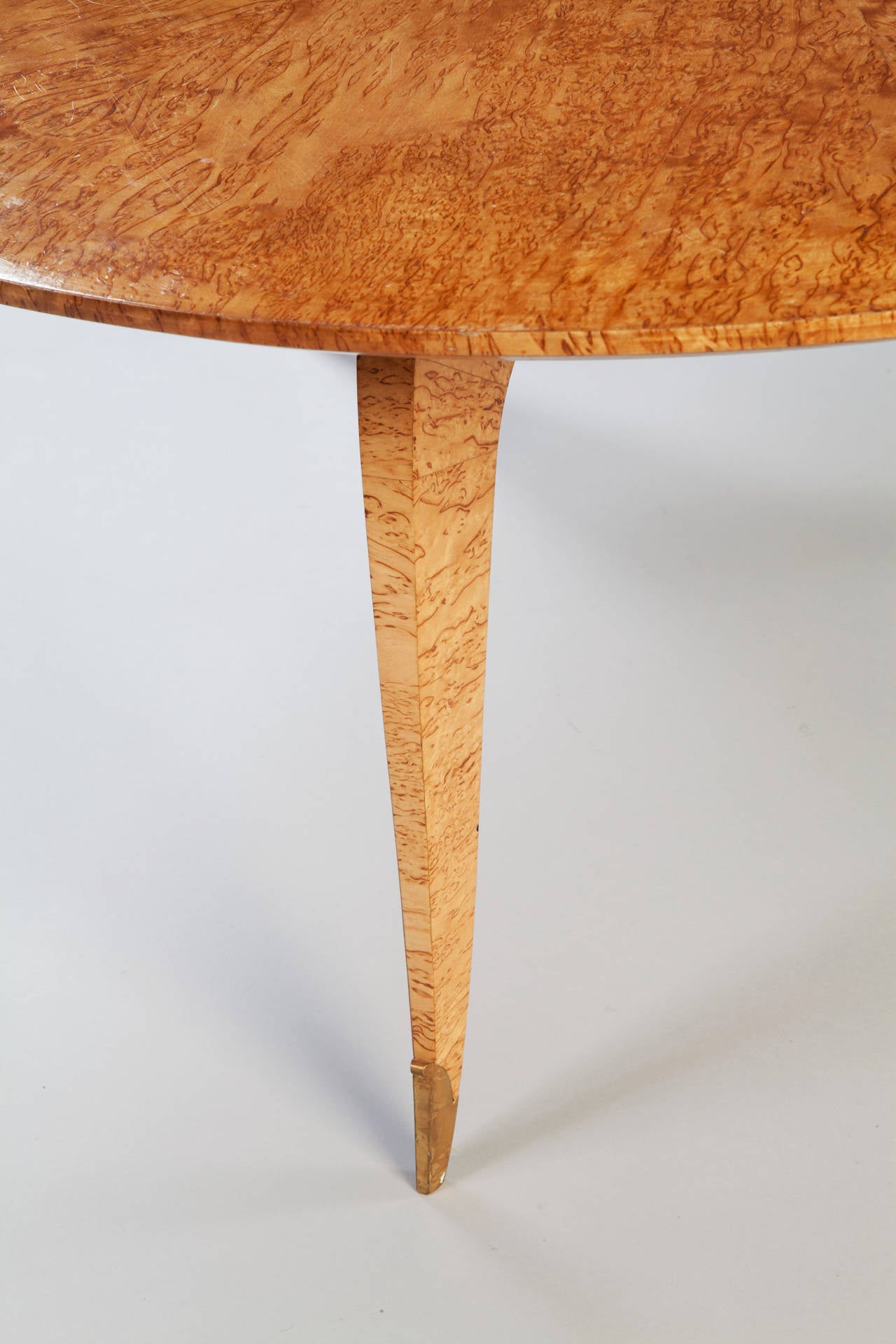 An elegant early twentieth century burr maple veneered circular low coffee table, the three tapering sabre legs terminating in gilt bronze sabots. By Jean Pascaud.

Jean Pascaud was born in Rouen in 1903. He took a degree in engineering from the