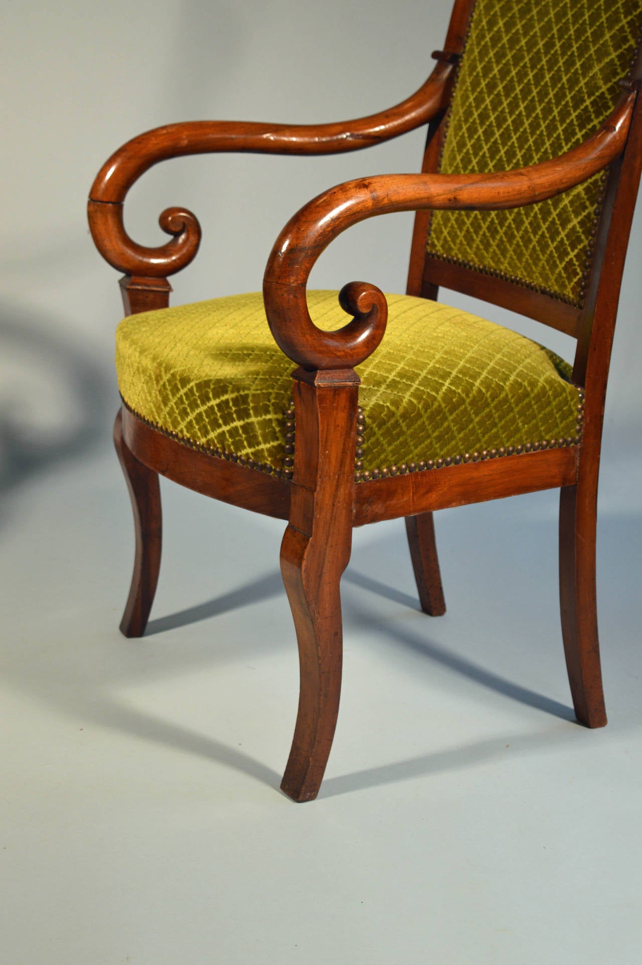 A pair of early nineteenth century mahogany fauteuils with curved arm supports, straight backs and sabre legs.