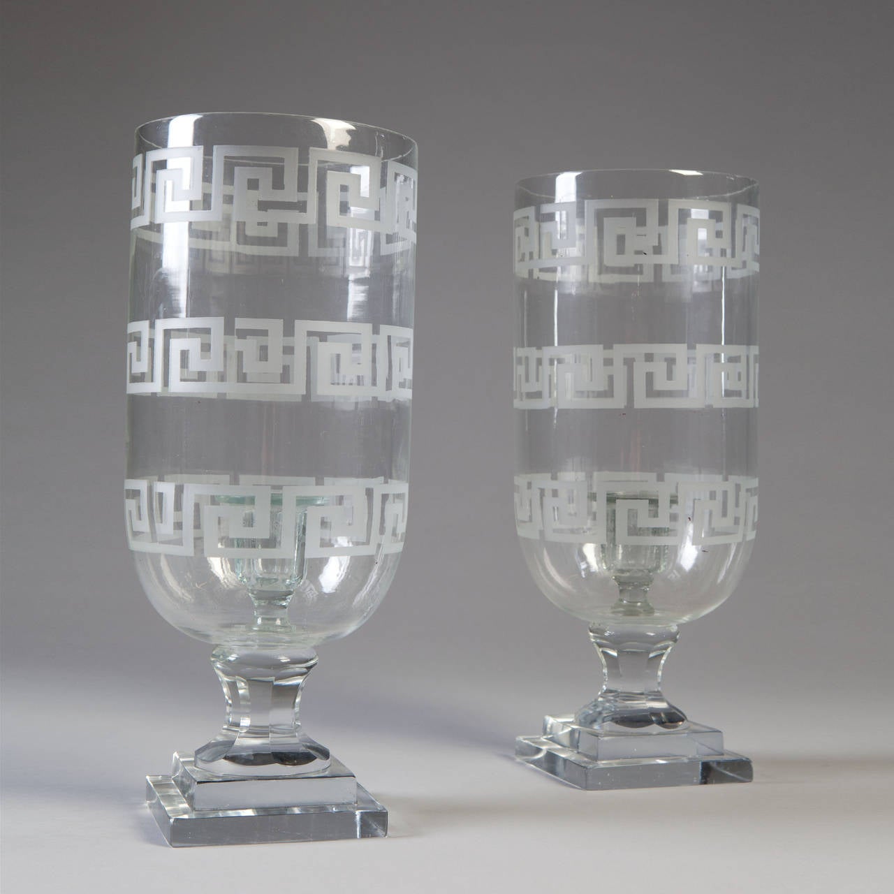 A fine set of four glass hurricane shades engraved with Greek key pattern throughout, supported on square bases