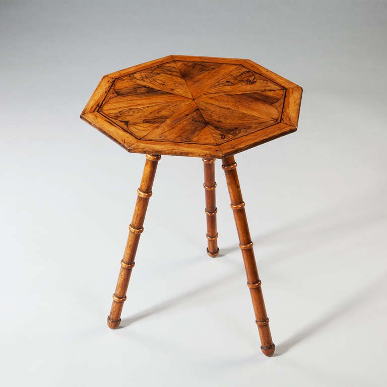A fine walnut occasional table, the octagonal top inset with highly figured walnut panels, the whole raised on three faux bamboo stylised legs.