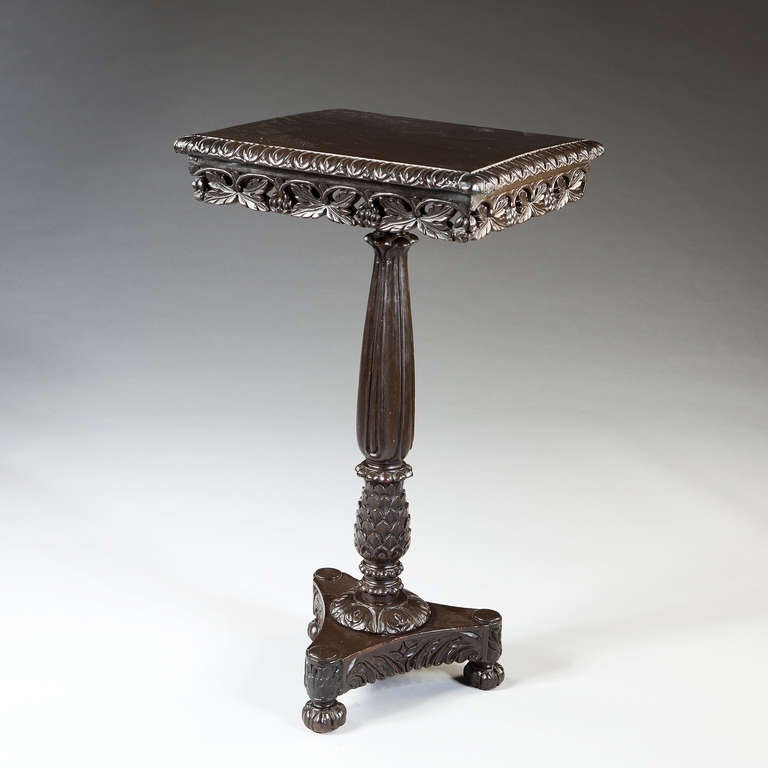 A fine mid-19th century ebonised indian hardwood tilt top table, the polished top with stylized egg and dart thumb moulding above pierced foliate carving, the top raised on a fluted baluster column, ensuing from a pineapple, the whole raised on a