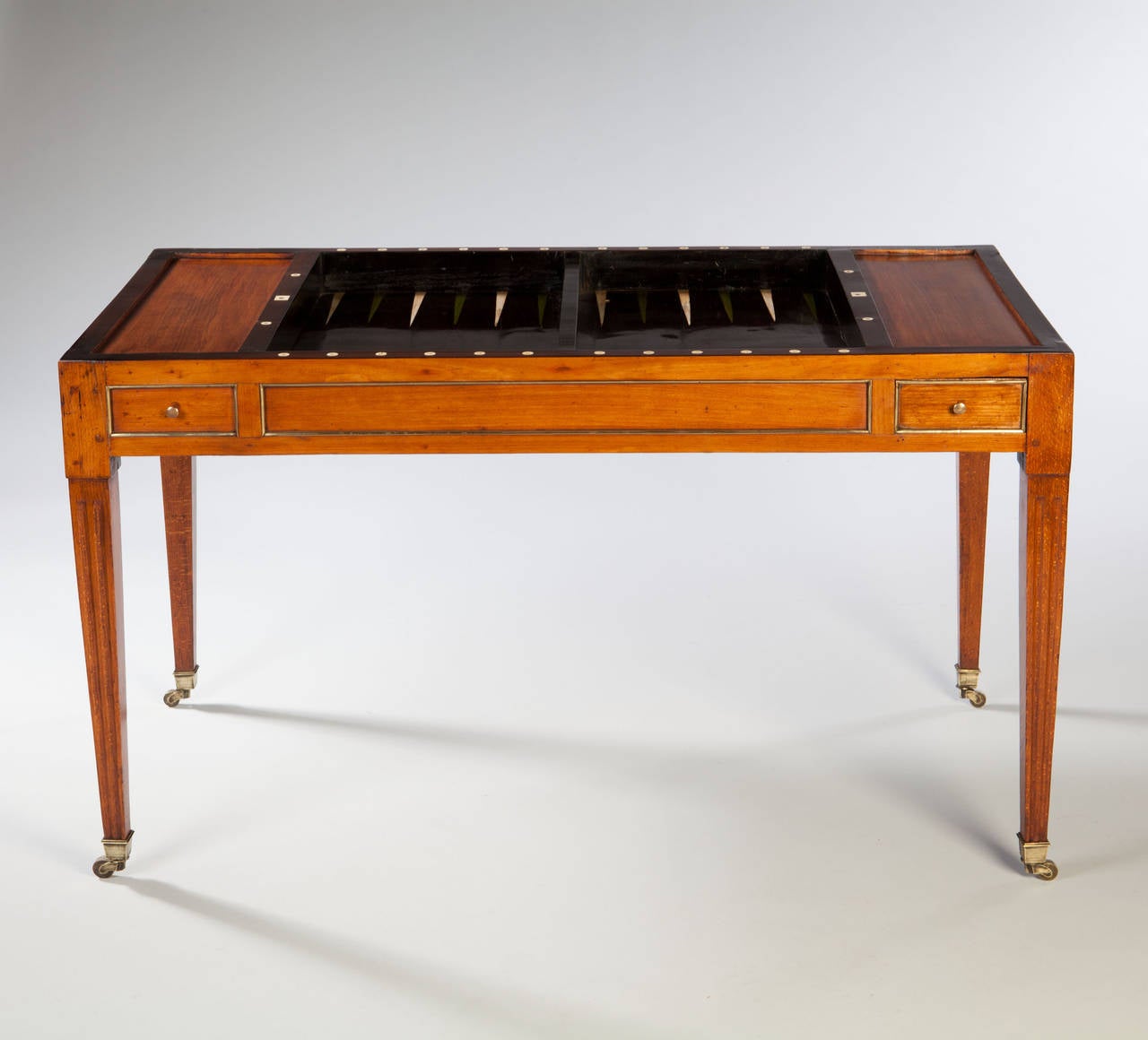 A Louis XVI period tric trac or games table. The removable leather lined writing surface having reversible baize lined playing surface, over ebony lined and ivory and rosewood inlaid backgammon well. The table is raised on square tapering legs