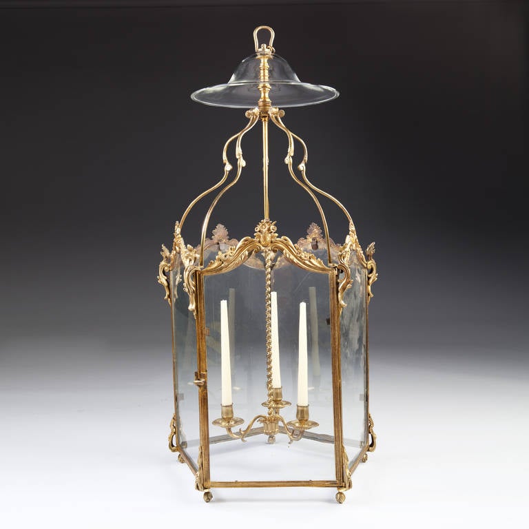 A rare mid-18th century, Louis XV transitional gilt bronze five sided hall lantern, each face glazed and flanked by cast bronze mounts and finely cast and chased floral sprays. Retaining its original three branch chandelier element with unusual
