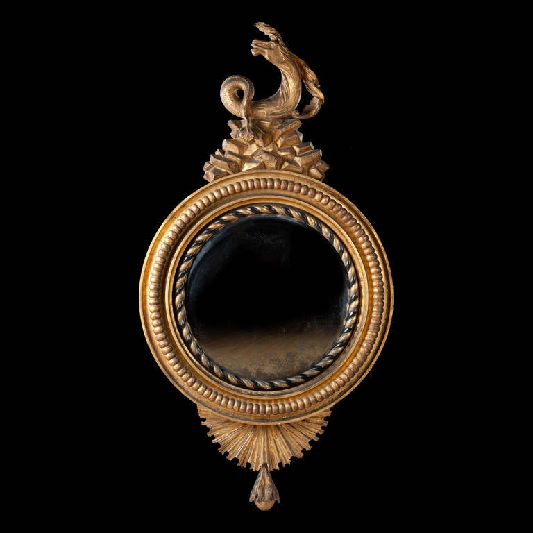 A fine early 19th century Regency convex mirror of large scale decorated with beading and rope twist ebonized and gilt boarders. 

A 'hippocamp' 1  surmounts the convex mirror perched on an outcrop of gilt rocks. The lower frame is shown as a