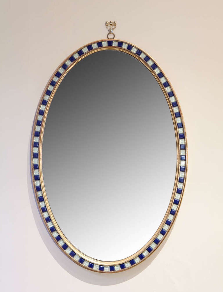 A Irish oval mirror with alternating bevel cut opaque and blue glass lozenges.