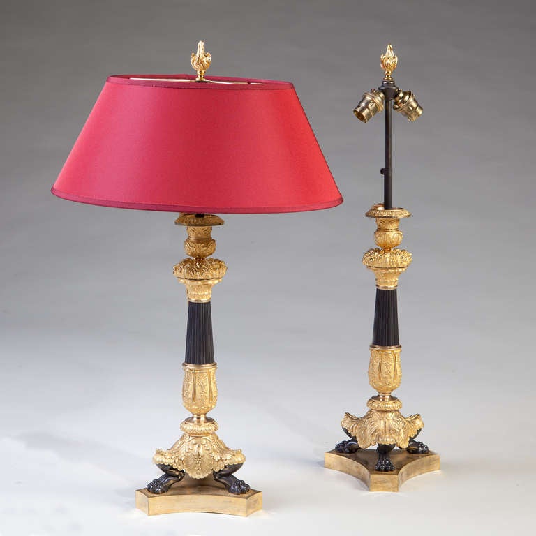 Each with gilt and patinated bronze columns and tripod feline legs, the whole raised on concave triangular bases. The nozzles supporting adjustable double lamp fittings.