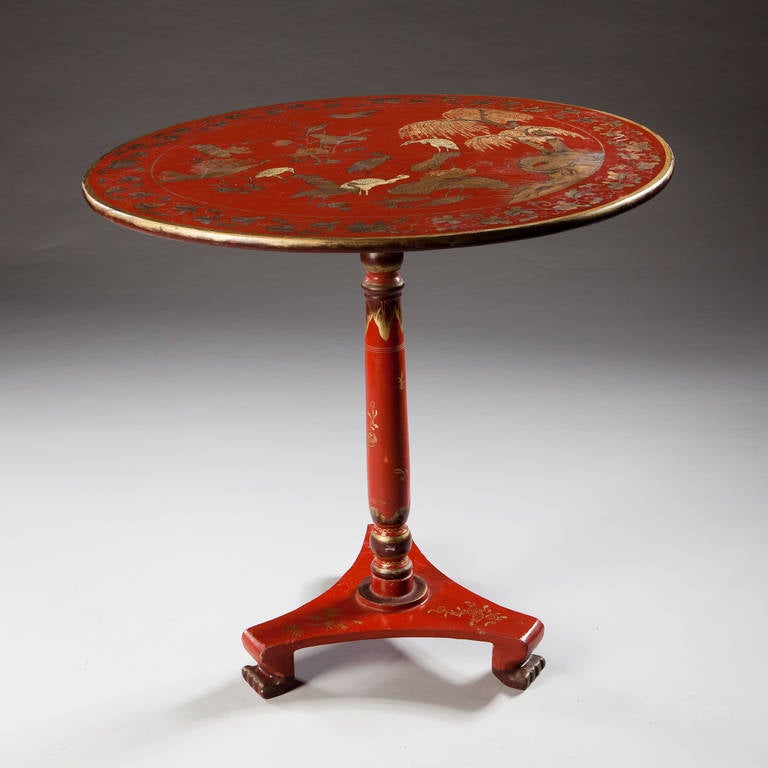 A charming circular red lacquer tilt-top table supported on a column base and standing on three paw feet. The top decorated throughout with foliage and birds  in two tone decoration.