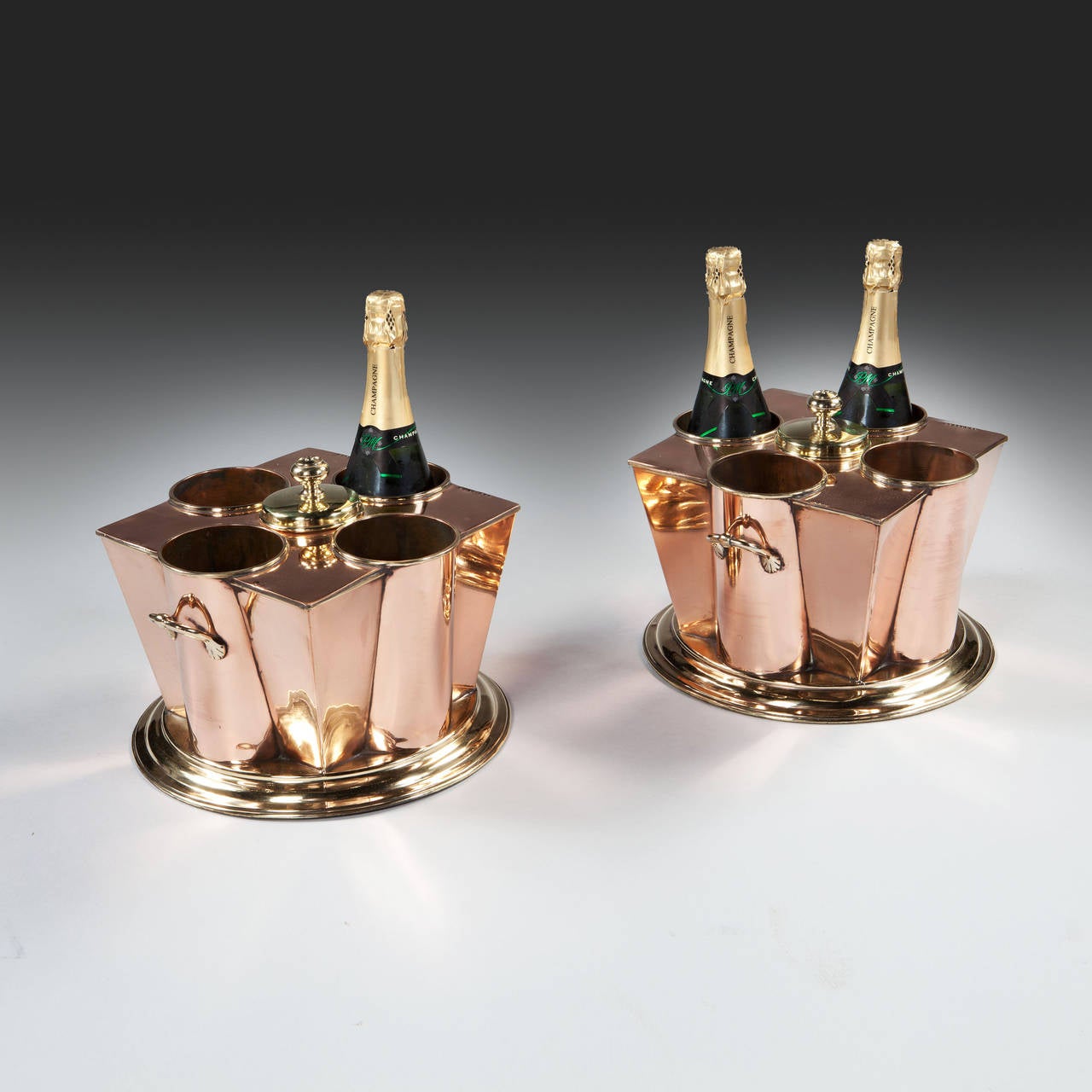 A fine pair of mid 20th century copper and brass champagne coolers of square tapered outline, each fitted with four bottle holders with twin handles on a circular stepped base, each stamped 'WHITE STAR' 'SS BOSTON'. 

Attributed to G. PEAK & CO.