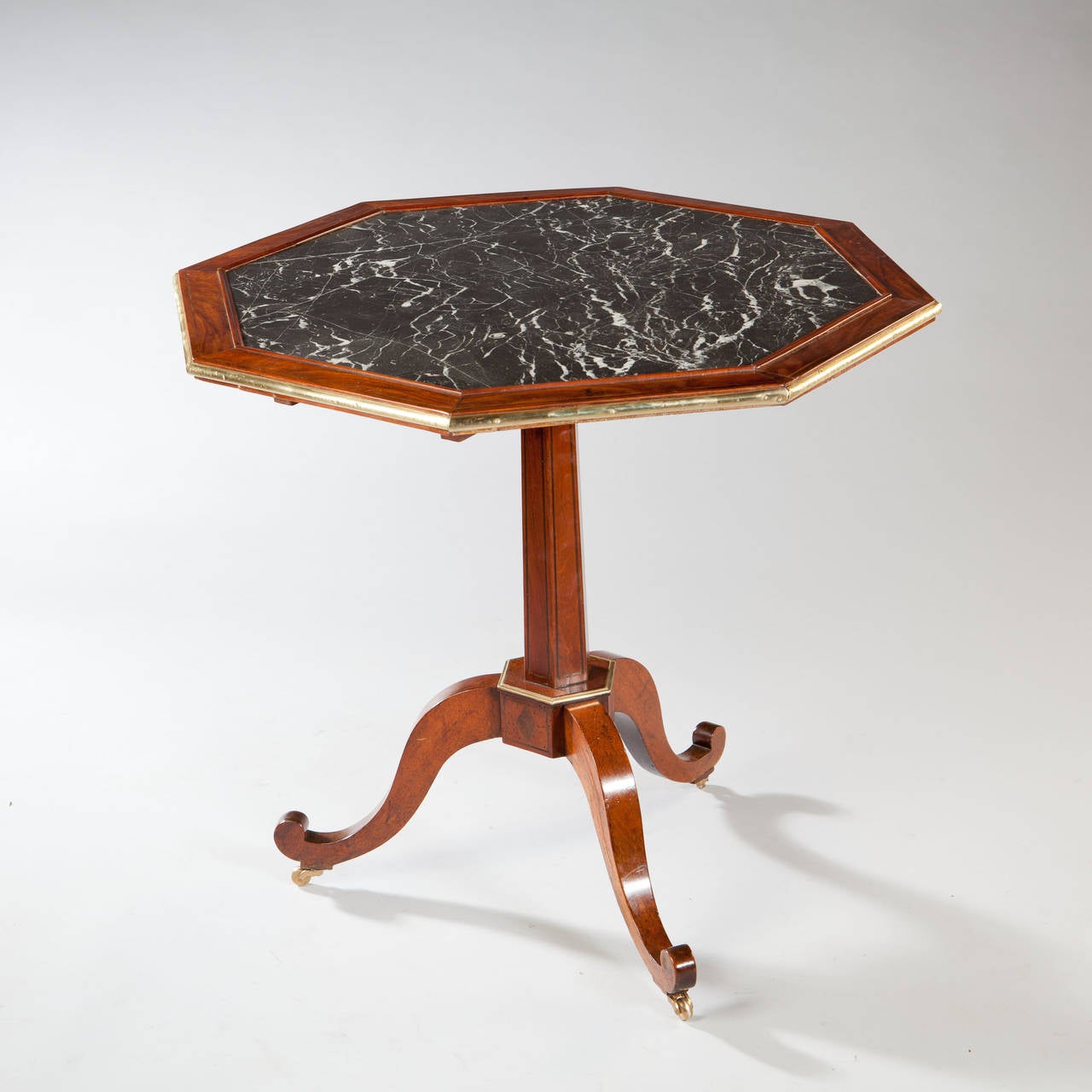 A fine late 18th century French tilt top table in the Georgian English manner. The octagonal top inset with a highly figured Nero Marquinia marble and bordered with cuban mahogany and polished brass borders. The tilt top supported on a hexagonal