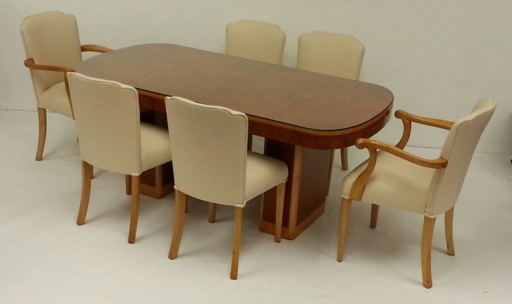 An impressive Art Deco dining table and six chairs by Harry and Lou Epstein (1895-1970)
The table raised on two pedestals and finished in a golden bird's-eye maple and pale satin ash, glass top.
Four chairs and two carvers fully re-upholstered in