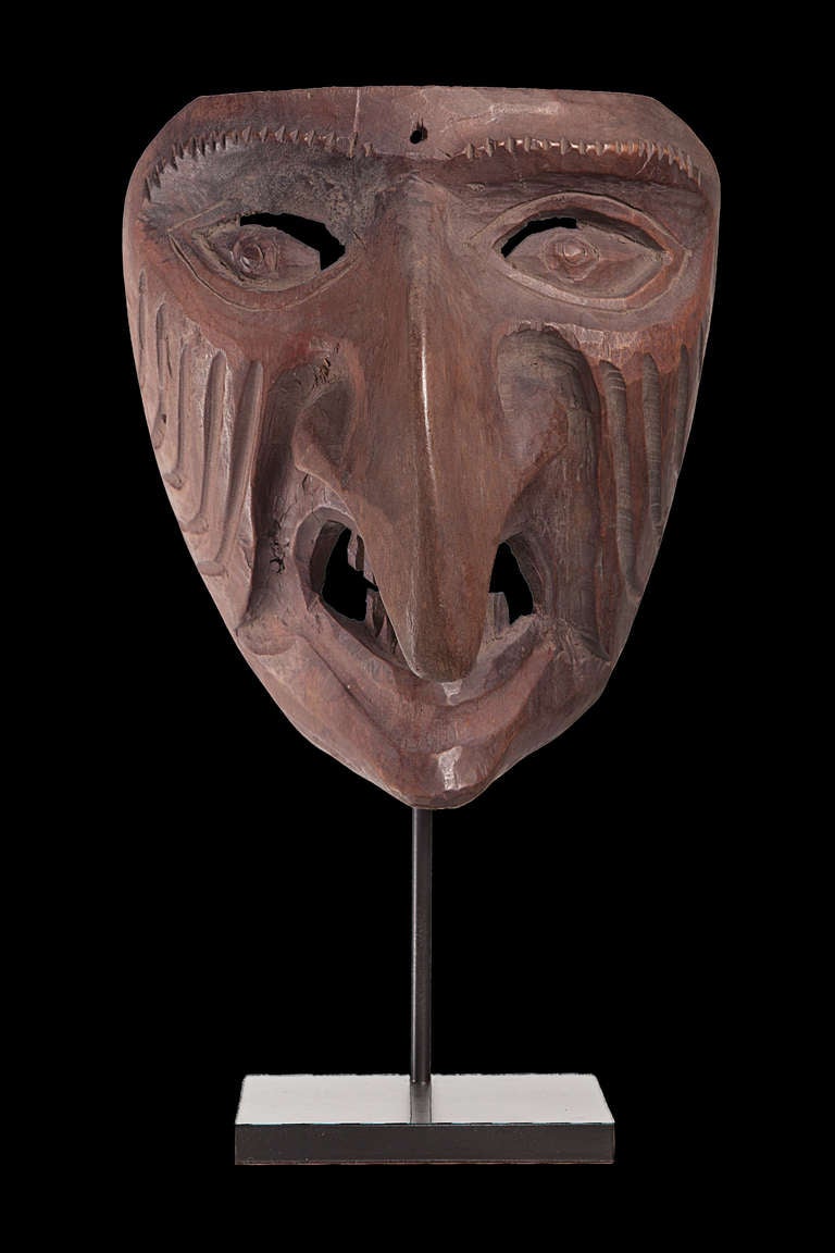 A mask with a scary and extremely strong expression. Representing a bad spirit, it reminds us to the Big Nosed Kanak Masks from New Caledonia.

Expertly mounted. 
All dimensions are without the mounting.