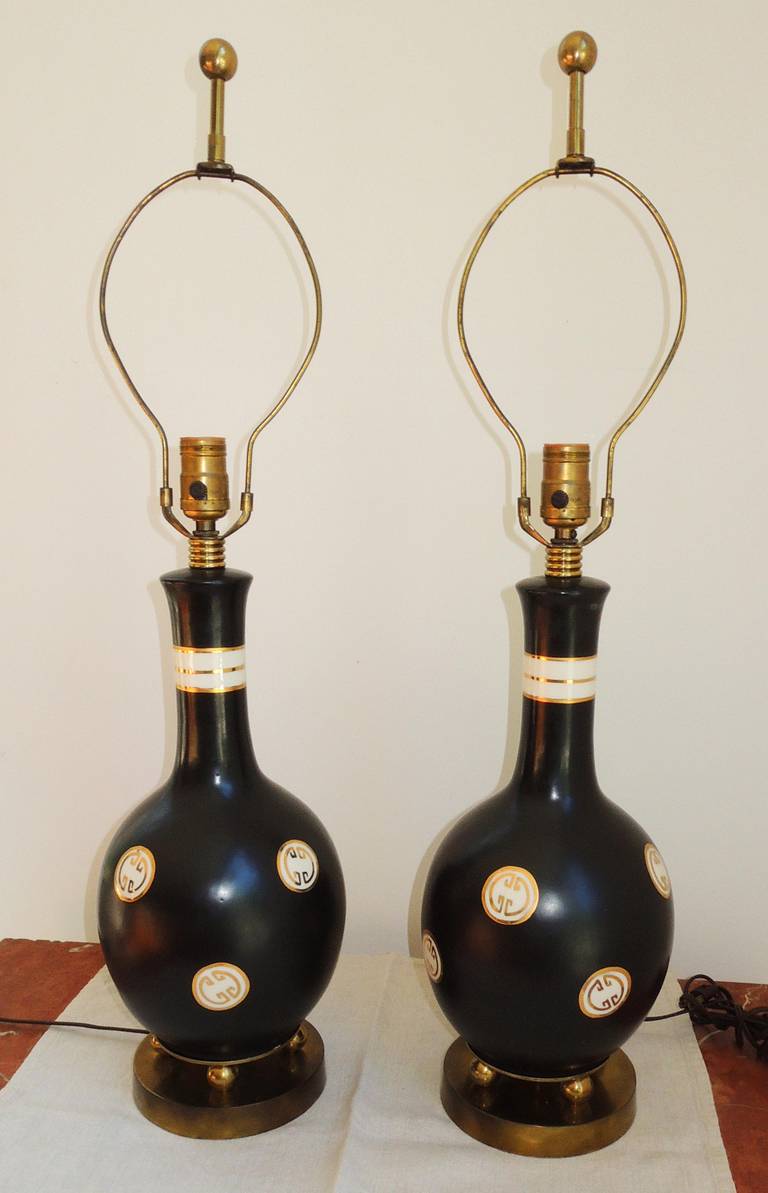 Hollywood glamour! Black ceramic gourd shape lamps decorated with white and gold Chinese motif. Note the brass ball feet, brass ribbing at the neck, original finials. The quality of the brass is very high.