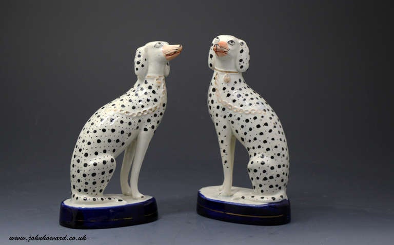 A fine pair of antique Staffordshire pottery figures of Dalmatain dogs modelled seated on cobalt blue bases.. The dogs are decorated with double spots which are underglaze. 

Literature  A-Z Staffordshire Dogs by Clive Mason Pope page 26 figure 5.