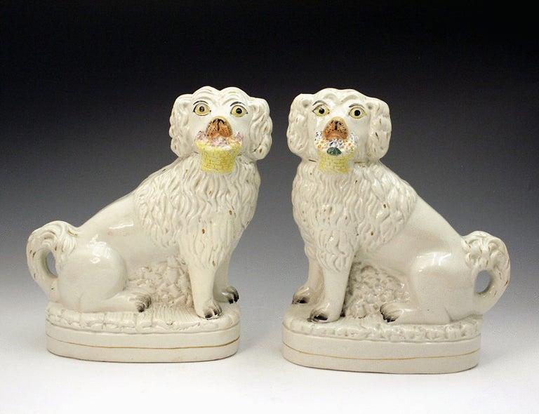 A pair of antique Staffordshire pottery figures of dogs with baskets in their mouths. 
One of the best pair of Flower basket dog figures produced and modelled sitting on bases. 

Literature: A-Z Staffordshire Dogs by Clive Mason Pope for