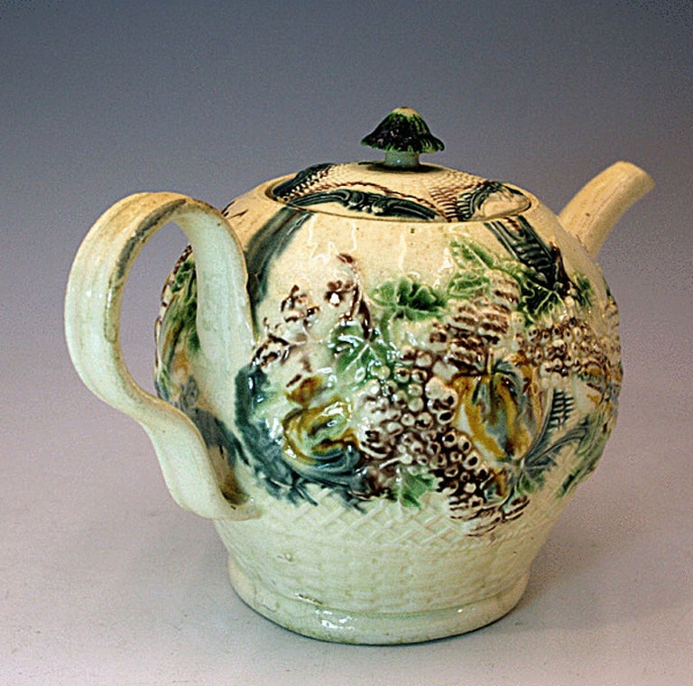 Antique Staffordshire pottery creamware teapot in colored glazes. Relief moulded decoration typical of the work of William Greatbach of Staffordshire in the circa 1765 period. A well colored and crisply modelled example. 

