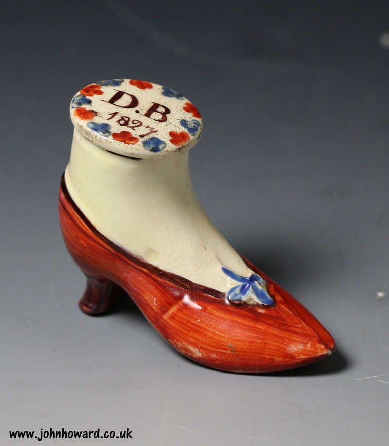 Antique Staffordshire pottery snuff box in the form of a shoe. The shoe is inscribed DB and dated 1827. Typical strong enamel color decoration. The screw top is original.