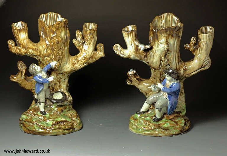 A true pair of Staffordshire pottery tree trunk figure group in underglaze colours.