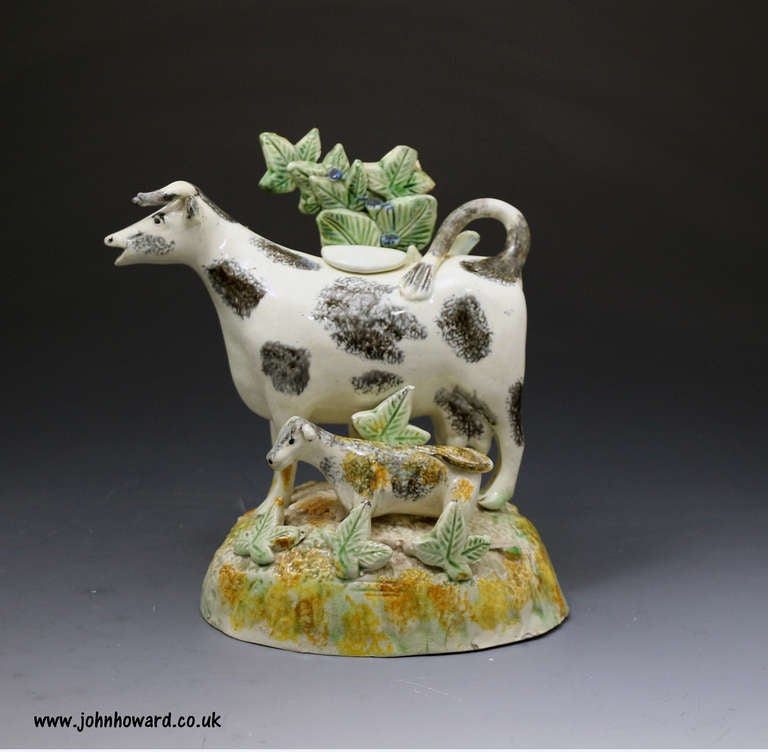 Antique Staffordshire or Yorkshire pottery figure of a cow in the form of a creamer.
This figure has added interest with the rare bocage feature not often found on cow creamers.
This figure is an early example from the late 18th century period in