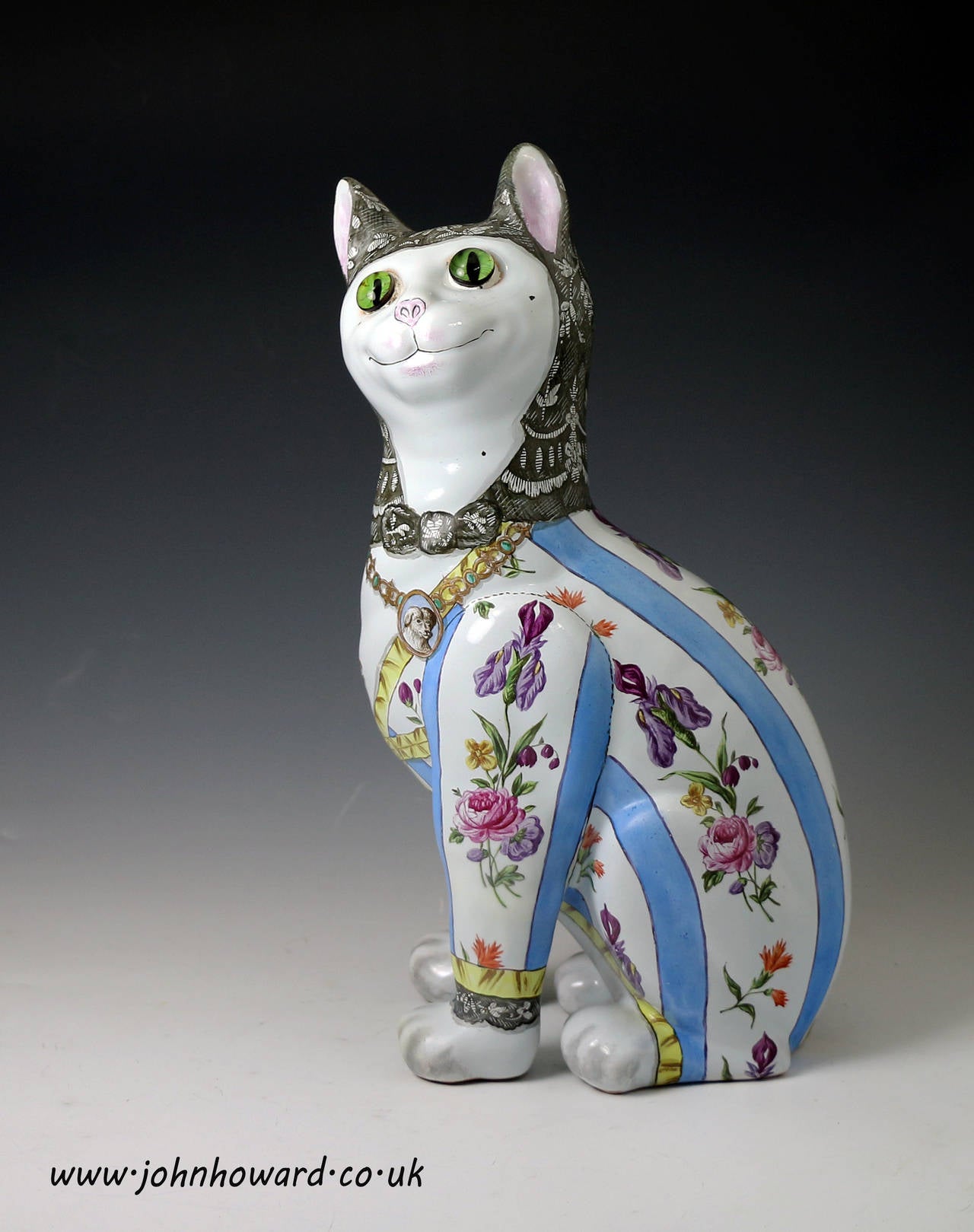 Antique pottery figure of a seated green eyed cat wearing a blue striped and floral outfit ( the glass eyes are very realistic). This figure is an original piece and signed E Galle Nancy.The figure captures the whimsical character of the feline, the