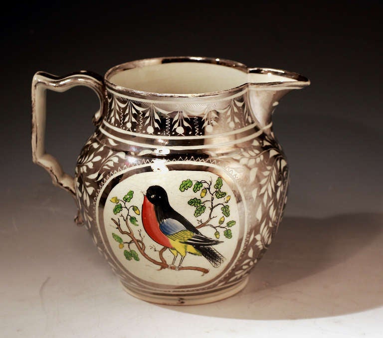 A fine antique pottery pitcher in silver luster and decorated with enamel colors with a rather pert looking Robin on both sides.
These Robin decorated jugs are increasingly rare and this piece is a very clean and strong example. Definitive