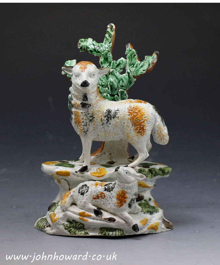 Antique Staffordshire or Yorkshire pottery figure a standing ewe with a lamb modelled on a rocky base with bocage. Pearlware glaze and decoarted in underglaze Pratt type colors.
