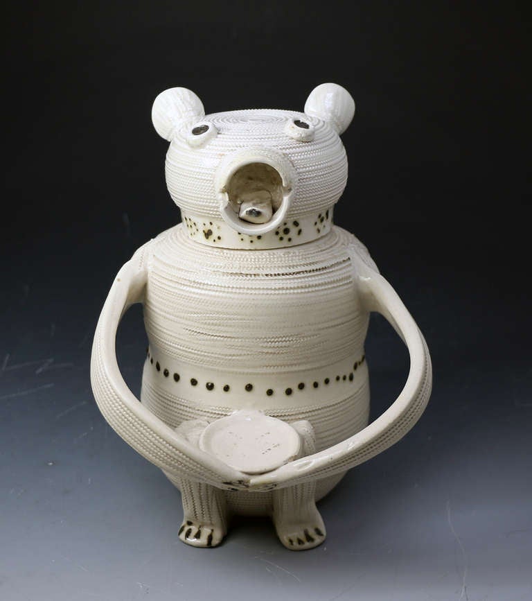 A rare Saltglaze Bear Jug and cover circa 1740.The figure has a slightly waisted cylindrical body with bands of rouletting around a central row of brown dots, a dish is held in the animals outstretched arms. The cover for this figure is a flattened
