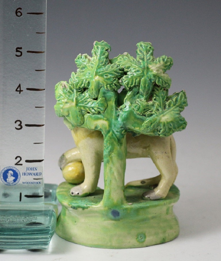 A fine antique Staffordshire pottery pearlware bocage figure of standing Lion with a paw resting on a ball. This figure was made in circa 1820.