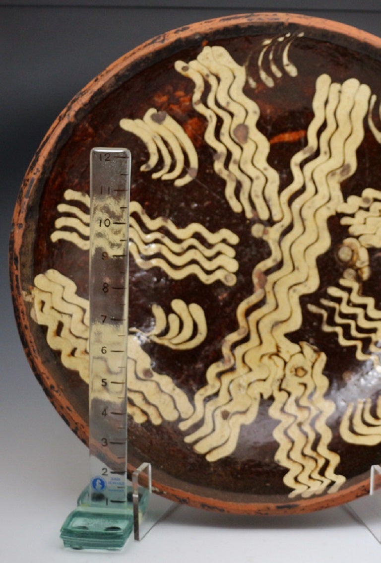 One of the largest circular slipware loaf dishes made at the latter end of the 18th century in England. 
The dish is very decorative with its wonderful dark chocolate ground and well applied cream coloured slip. 
The dish is is unrestored with