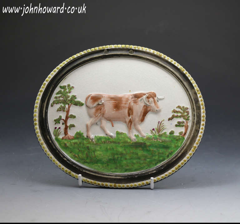 Antique Staffordshire pottery oval plaque with figure of a bull , pearlware galze and enamel colours c1820 

Antique Staffordshire pottery oval beeded border plaque with the figure of a bull standing in a meadow with trees. Pearlware glaze and the