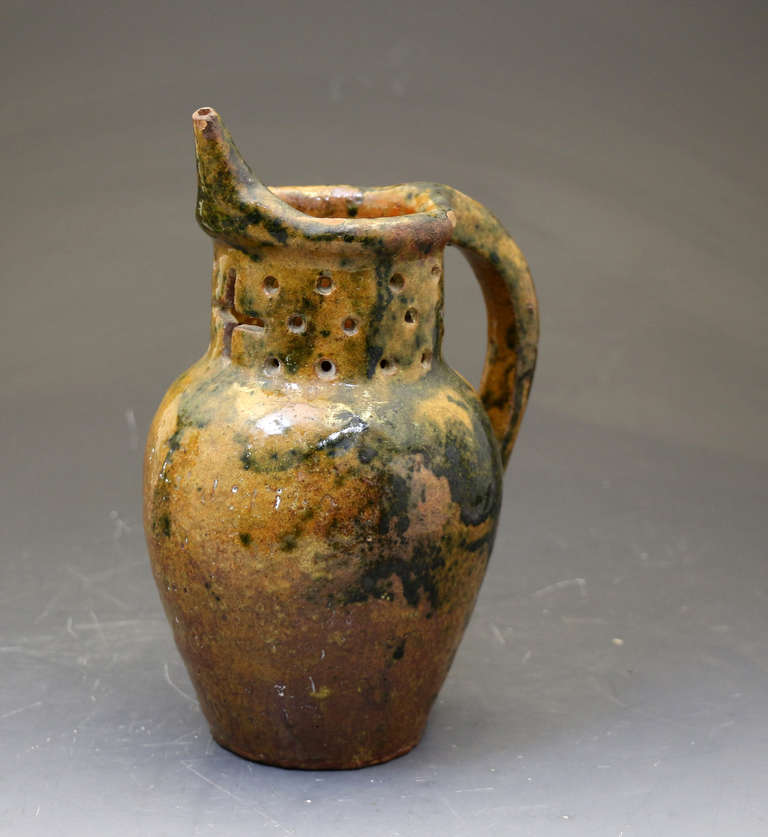 A Donyatt pottery puzzle jug modelled with the distintive spout associated with this Somerset pottery in SW England.
A good lusterous glaze and naively potted in the folk art tradition.
There is some indistinct signs on the body in scraffito