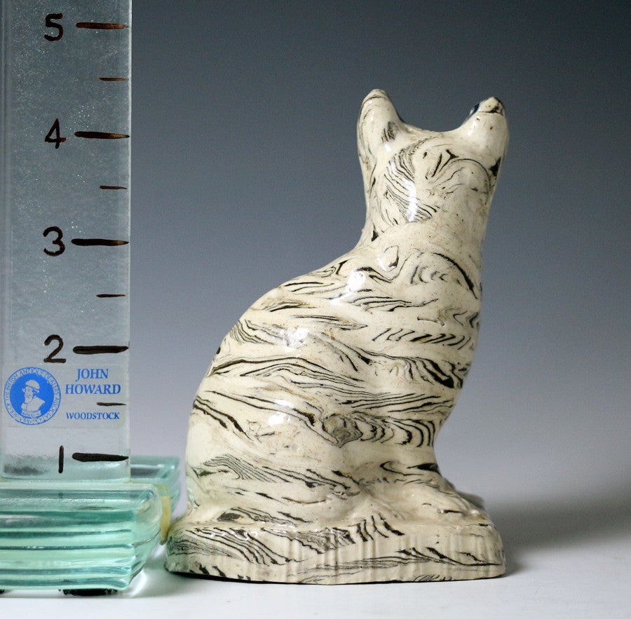 Antique English pottery agateware stone ware cat naively modeled sitting on a base. 
Staffordshire mid 18th century period circa 1760.