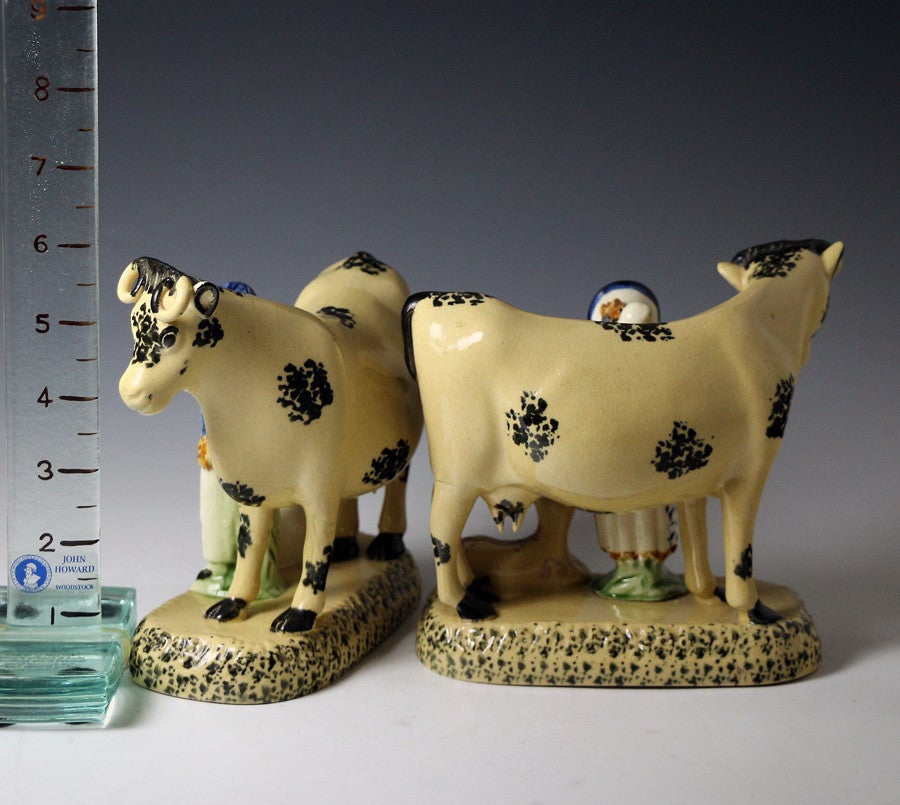 A fine pair of figures with standing cows and male and female attendants with calf and dog featured on the bases. 
The body of the figures is a light buff coloured clay which is decorated with Pratt underglaze colours. 
The figures are full of