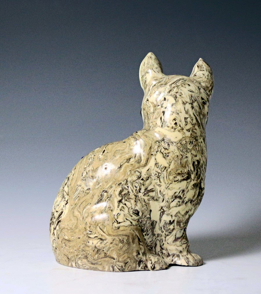 A fine antique English saltglaze agateware pottery figure of a seated cat carrying a mouse. 
The variegated clay decoration is excellently rendered and the saltglaze has patches of cobalt blue decoration at the ears and the body. Thie figure is a
