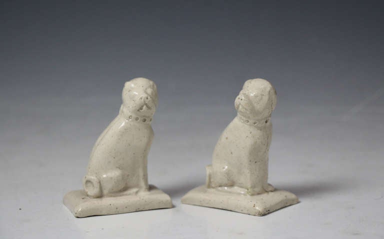 A rare pair of Staffordshire pottery saltglaze stoneware pug dogs from circa 1760. 
These naive pottery figures were produced at the beginning of the Staffordshire Potteries development to become the worlds major ceramic producer. 
The figures