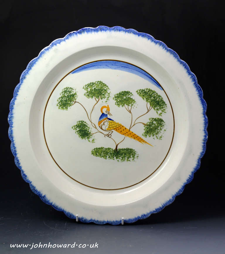 Antique pottery pearlware charger with Peafowl English early 19th century.
This rare blue edged piece is in very fine clean order with excellent rendition of the peafowl in the center panel. The orange head and cowlick like crest suggested to the