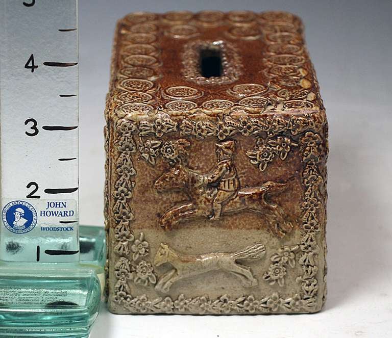 A rare English earthenware pottery stoneware saltglaze money bank. 
Decorated with relief molded images of a portly gentleman with a tankard of frothing ale, windmills and dogs. The side of the box has an image of a huntsman on horse chasing a fox.