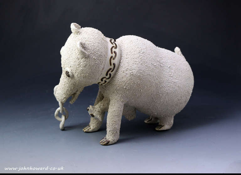 A salt-glazed stoneware pottery jug in the shape of a bear, with a dog attached to its chest. These figures appear whimsical, but in fact portray the cruel yet popular sport of bear-baiting, a legal recreation in England until 1835. These rare
